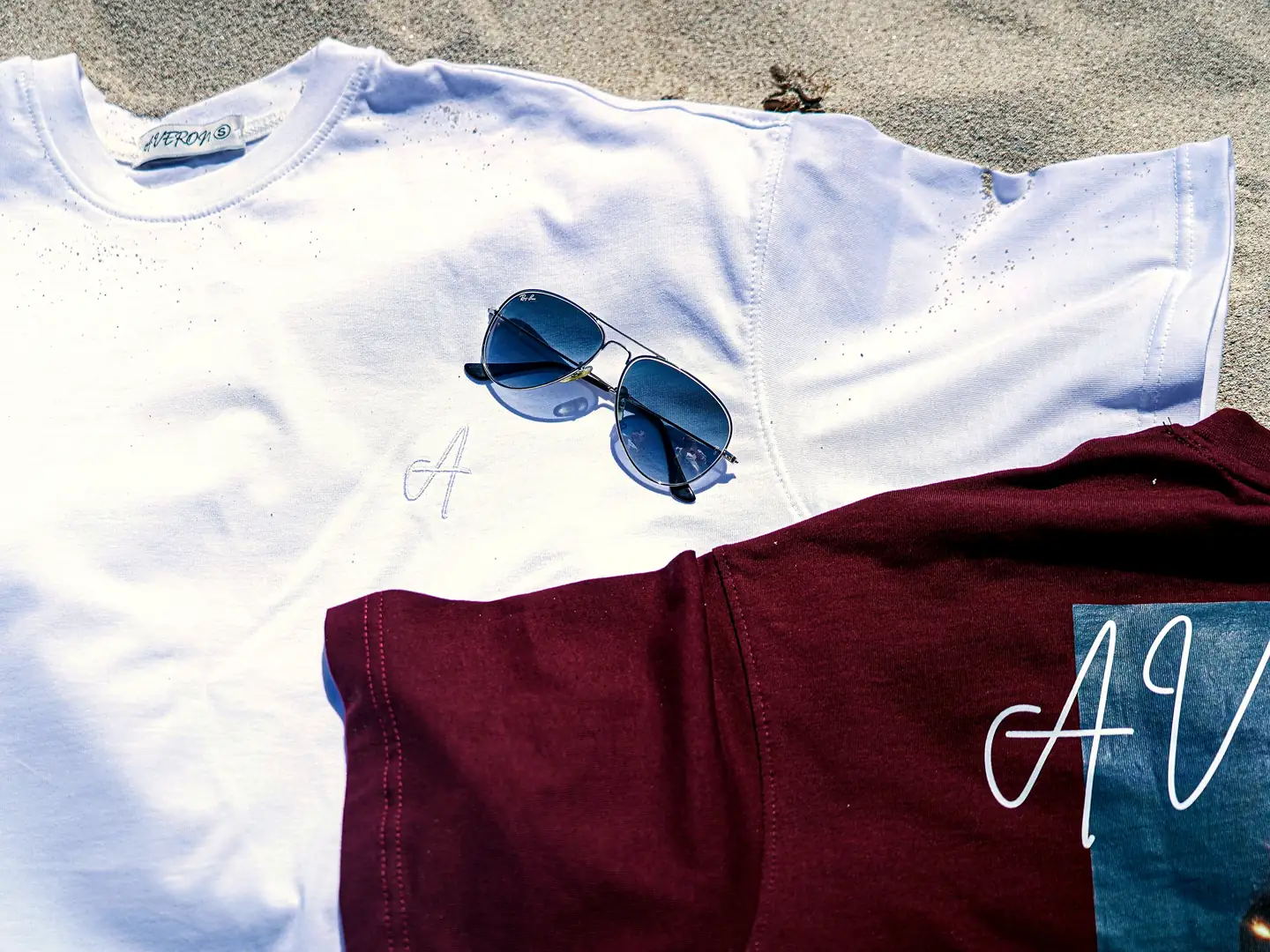 AVERON tees and sunglasses laid out on the beach